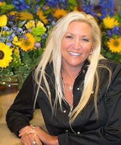 A woman sitting in front of some flowers